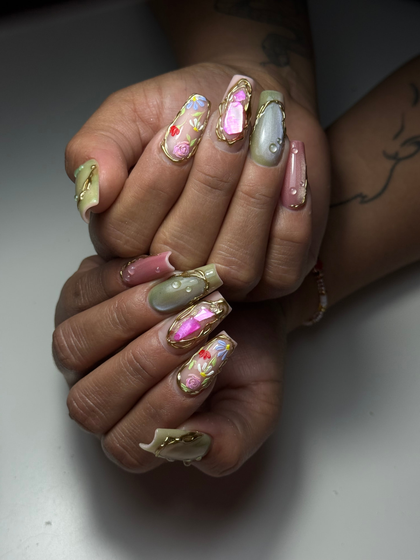 Diseño de uñas con nail art floral, tonos pastel y detalles dorados